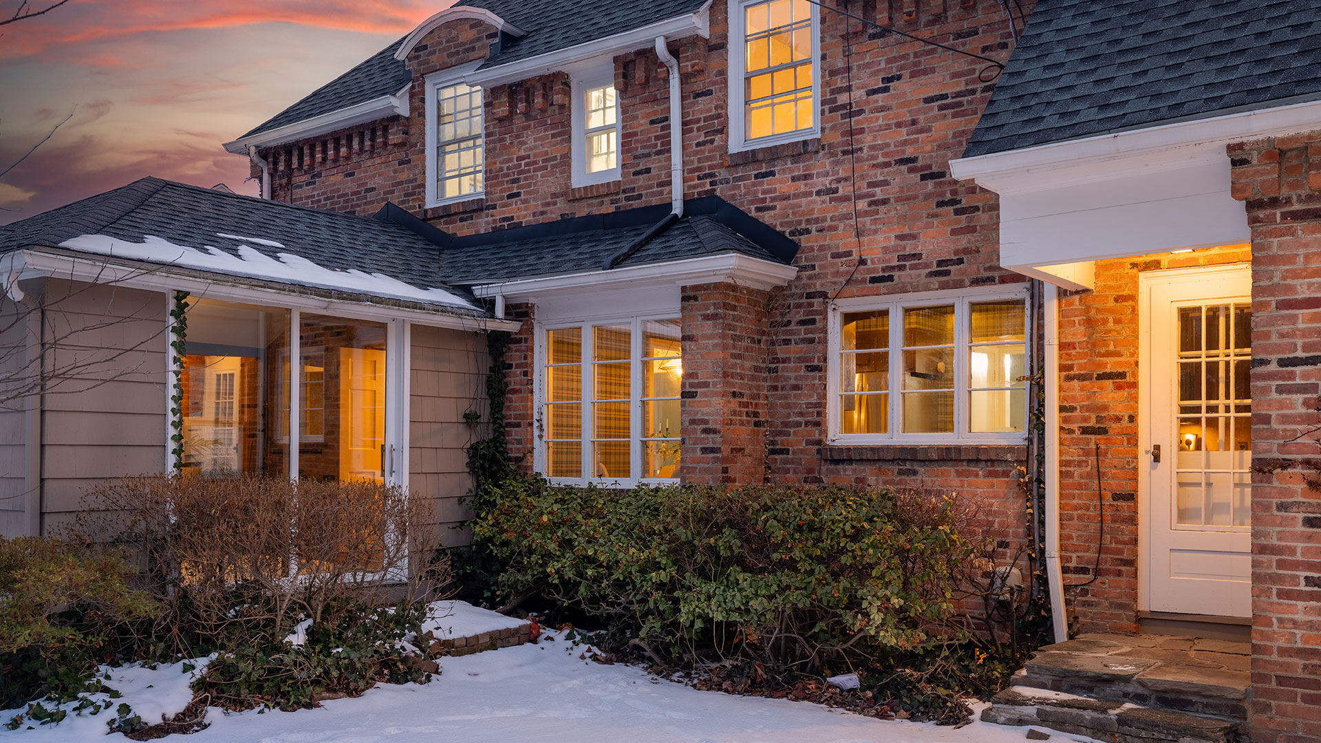 Home Buying Assistance. A brick house with a door and a snow covered ground