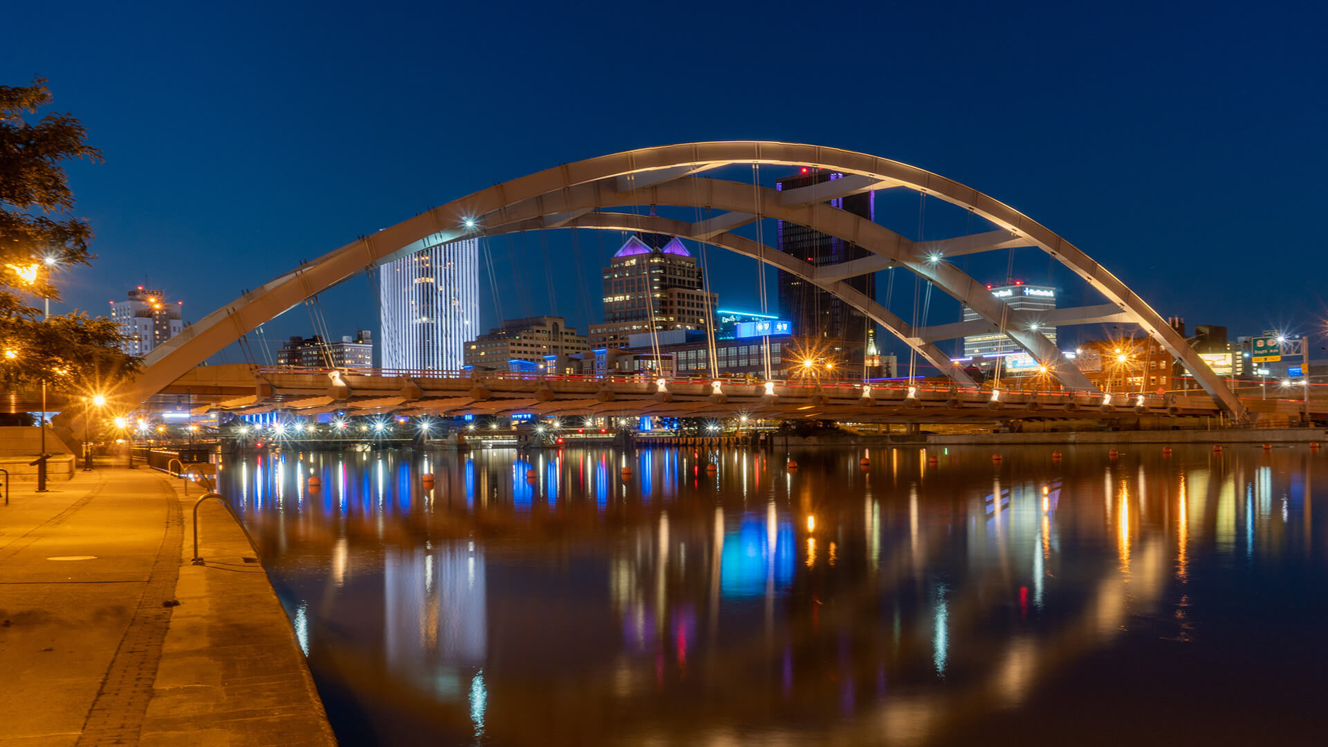 Bridge over river with city lights reflection.