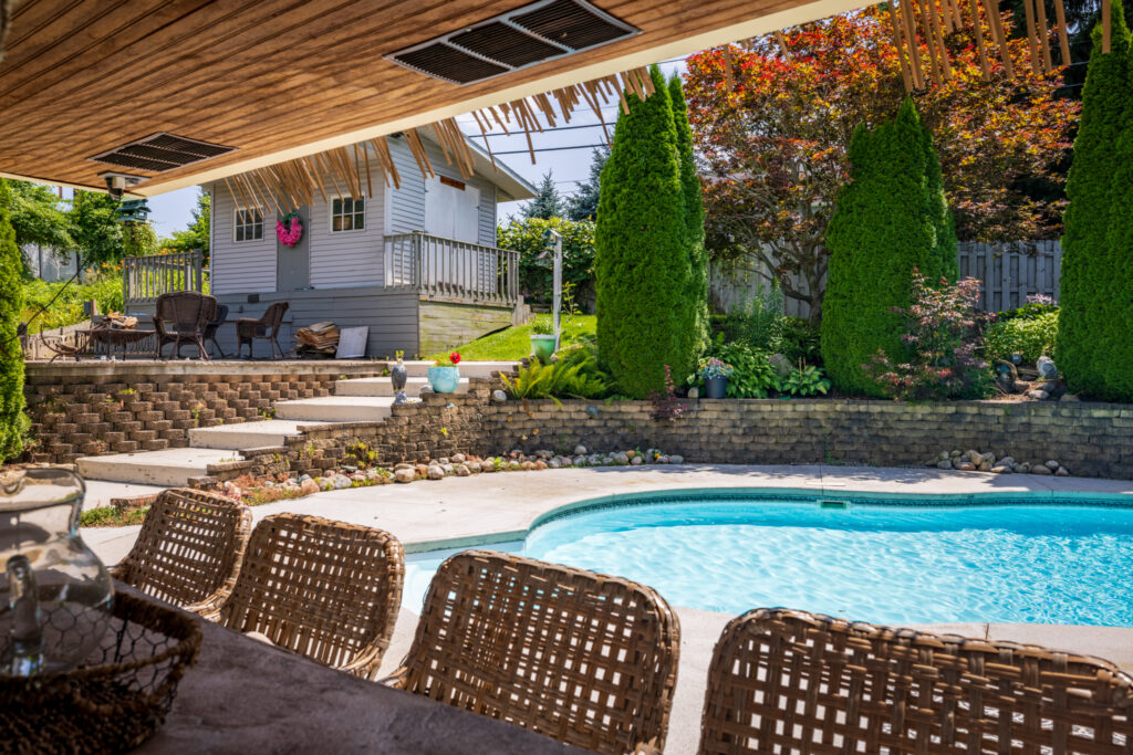 19 Warder Drive, Pittsford, Ny 14534 5 Saltwater swimming pool viewed from the tiki bar with mature landscaping surrounding the outdoor entertaining area.