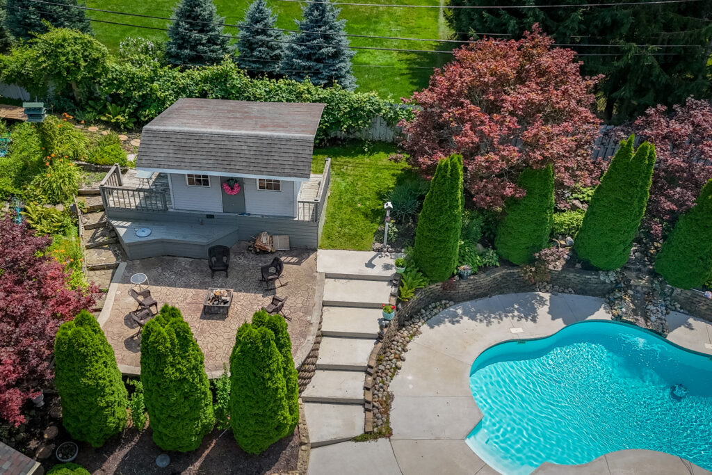 19 Warder Drive, Pittsford, Ny 14534 7 Aerial view of the landscaped backyard featuring gardens, patios, pergola, pool, and outdoor living spaces.