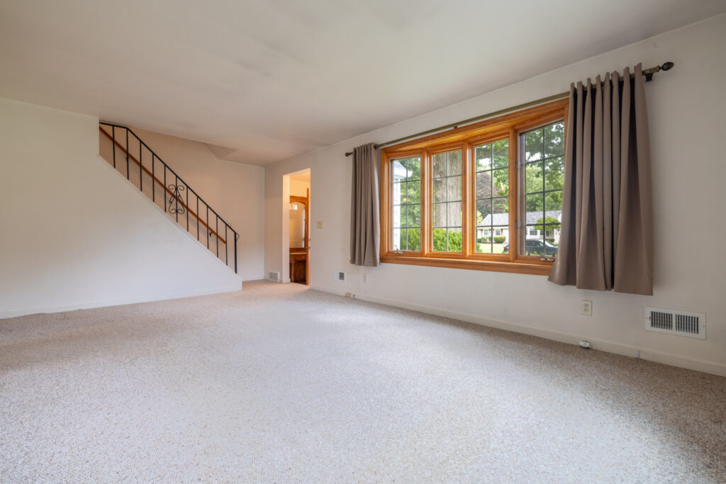9 Brewster Lane, Rochester, NY 14624 2 Living room at 9 Brewster Lane in Gates, NY with bay window and hardwood floors beneath carpeting