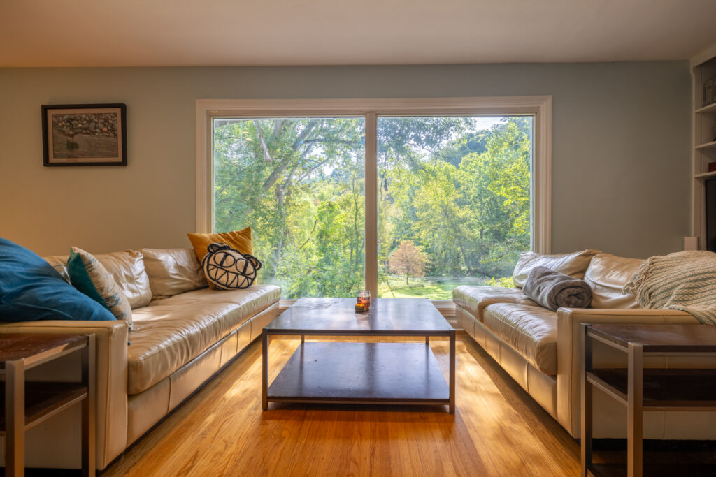 112 Burrows Hills Dr, Rochester, NY 14625 5 Oversized living-room picture windows overlooking the wooded backyard at 112 Burrows Hills Drive