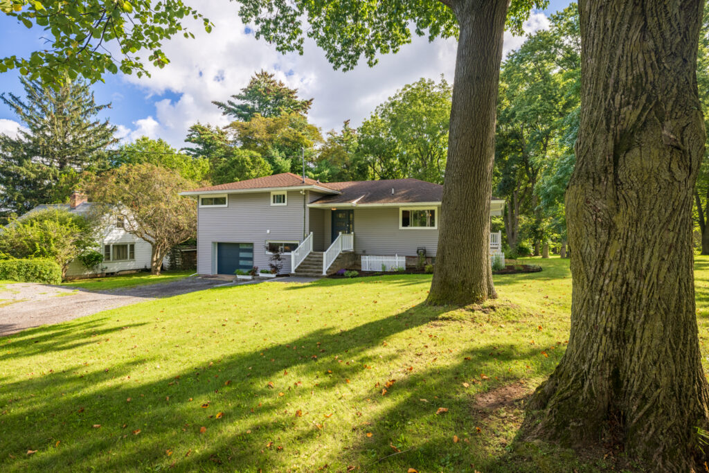 166 Moseley Rd, Fairport, NY 14450 1 Front exterior of the split-level home at 166 Moseley Rd Fairport NY, framed by mature trees and lawn.