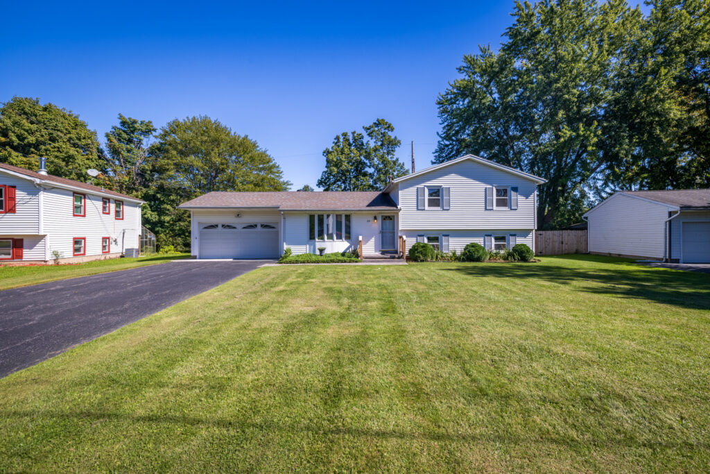 69 Cedarhurst Dr, West Henrietta, NY 14586 1 Split-level home at 69 Cedarhurst Drive with an attached two-car garage, wide driveway, and front lawn.