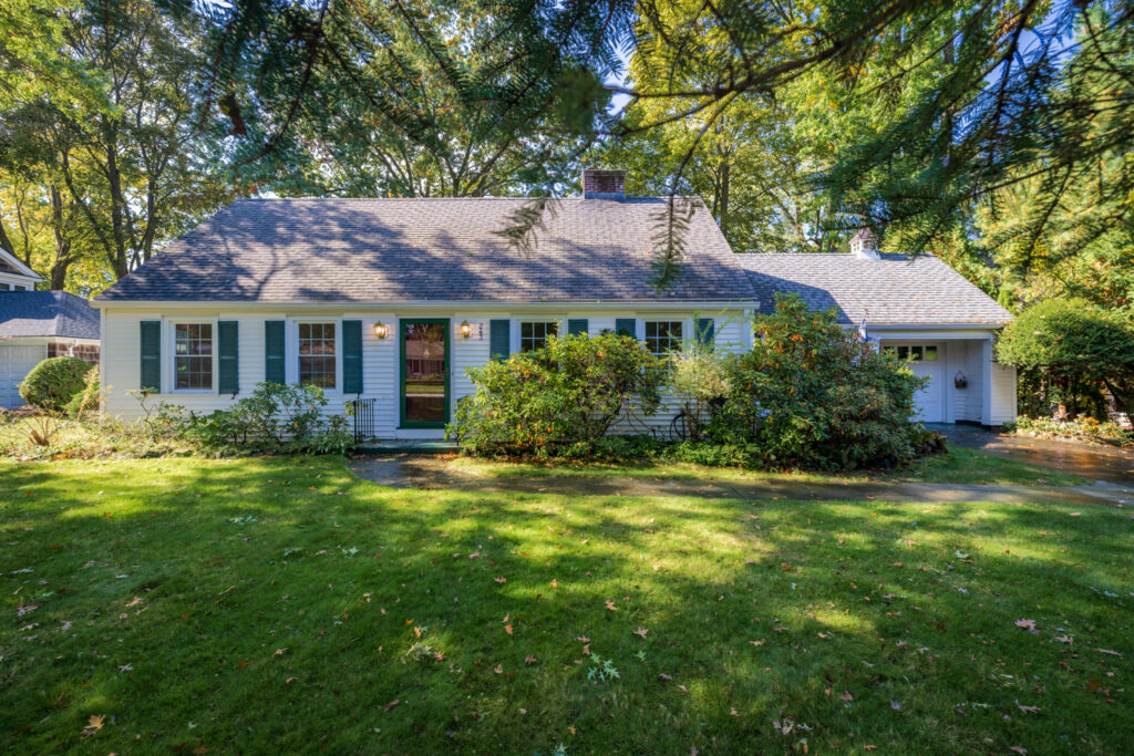 Charming 1947 Cape Cod-style home with white siding, contrasting shutters, mature trees and established landscaping at 243 Overbrook Road Pittsford NY