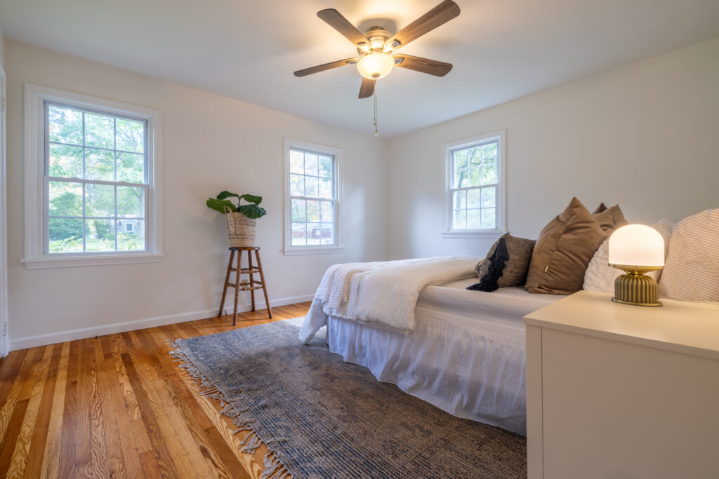 Bright first-floor primary bedroom with neutral walls, ceiling fan and multiple windows at 243 Overbrook Road Pittsford NY